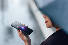 Woman using voice assistant on smartphone in the rain 