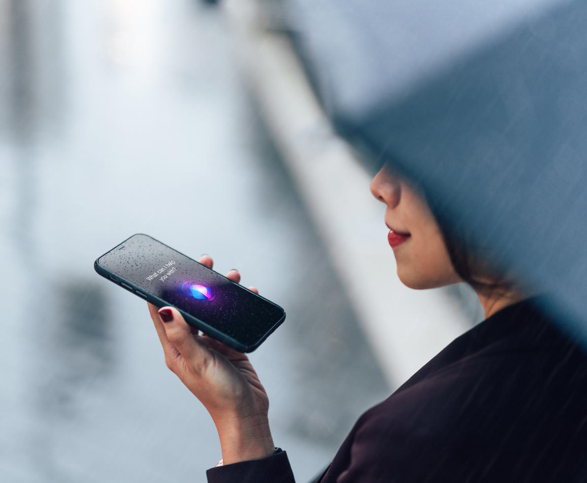 Woman using voice assistant on smartphone in the rain 