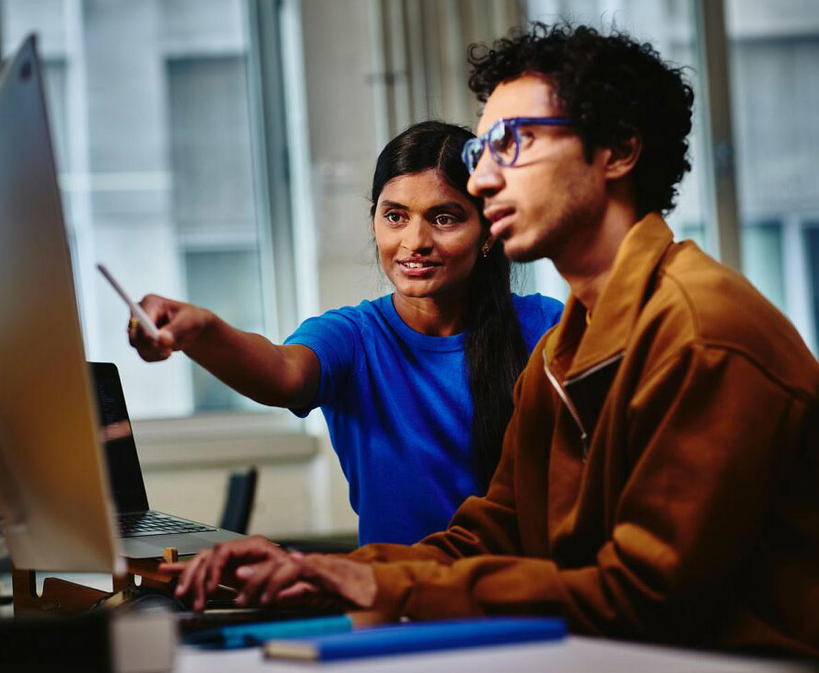 diverse coworker pointing to desktop screen